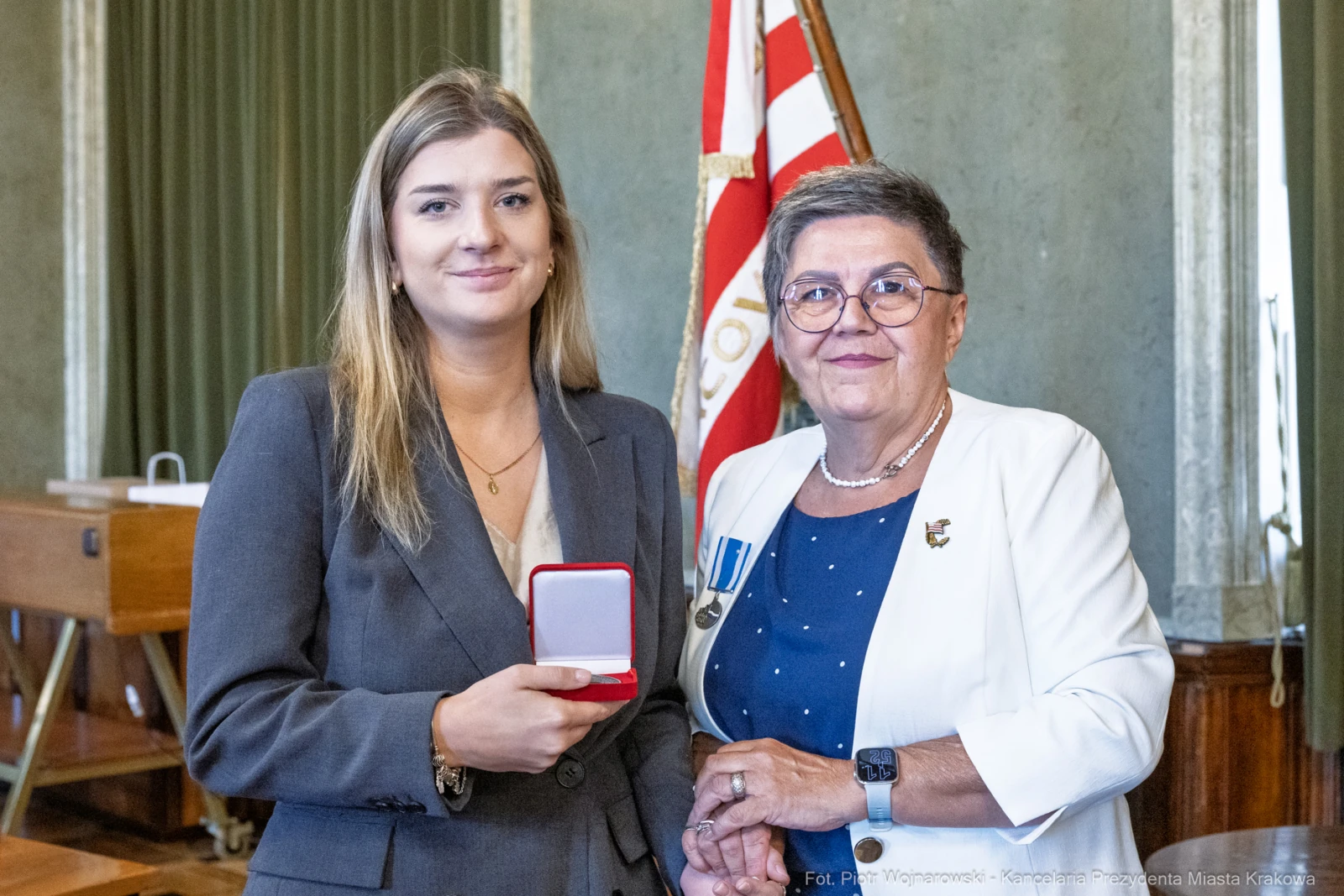 Wręczenie odznaczenia przez kobietę w okularach młodszej kobiecie trzymającej medal w pudełku.  Autor: Piotr Wojnarowski