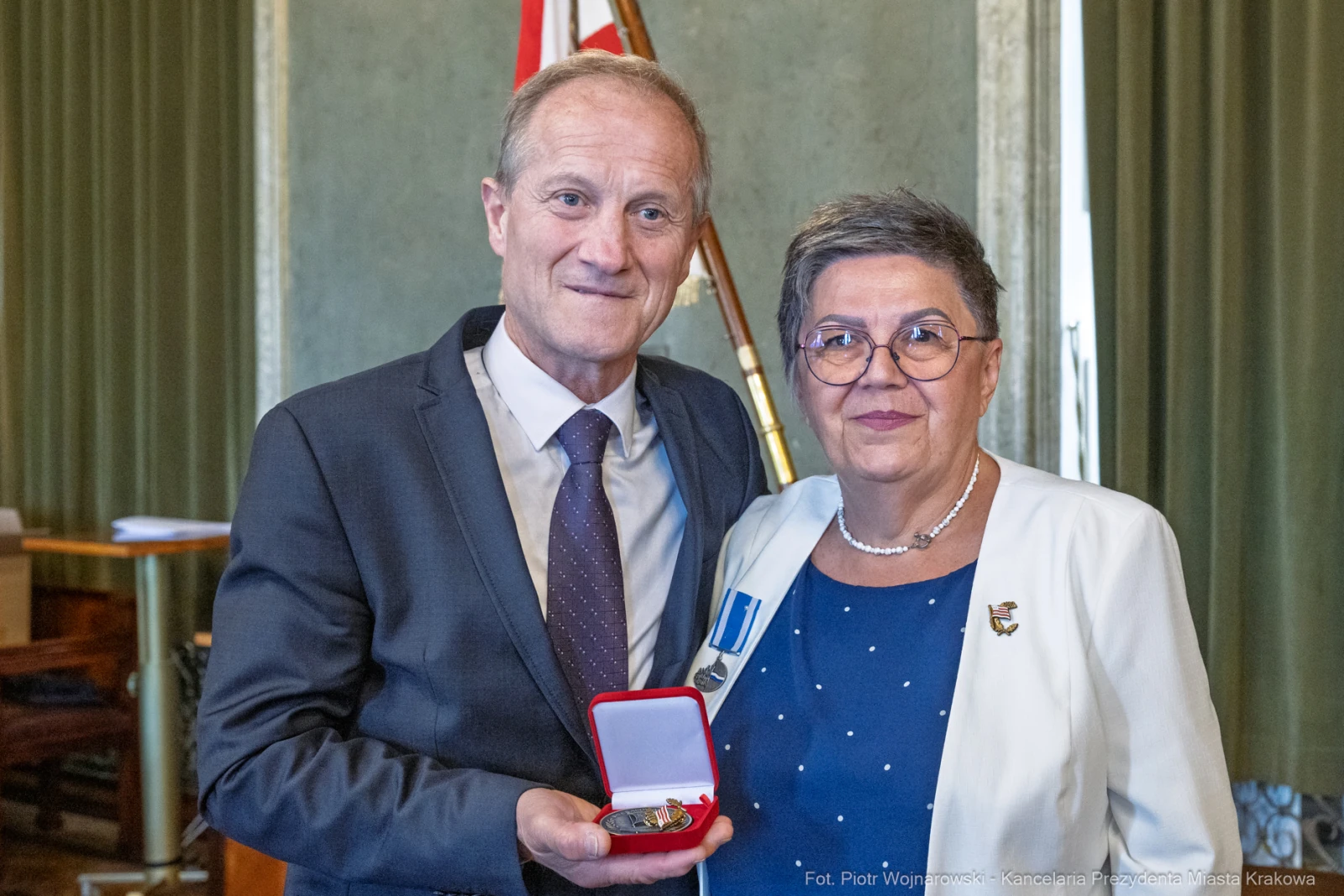 Mężczyzna i kobieta trzymają medal w eleganckim otoczeniu.  Autor: Piotr Wojnarowski