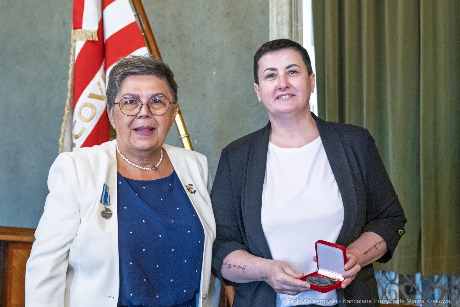 Dwie kobiety z medalem w eleganckich strojach, jedna z nich uśmiechnięta.  Autor: Piotr Wojnarowski