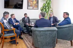 Spotkanie grupy mężczyzn w biurze, przy okrągłym stole, z filiżankami kawy.