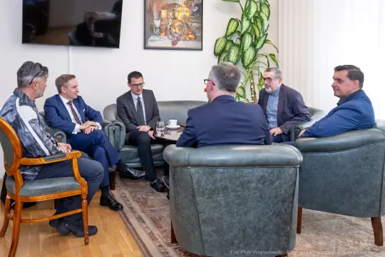 Spotkanie grupy mężczyzn w biurze, przy okrągłym stole, z filiżankami kawy.