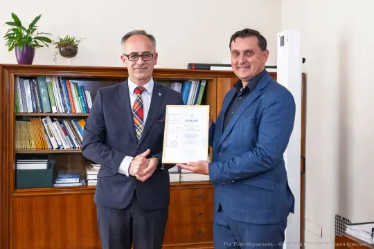 Dwóch mężczyzn trzyma dyplom w biurze.