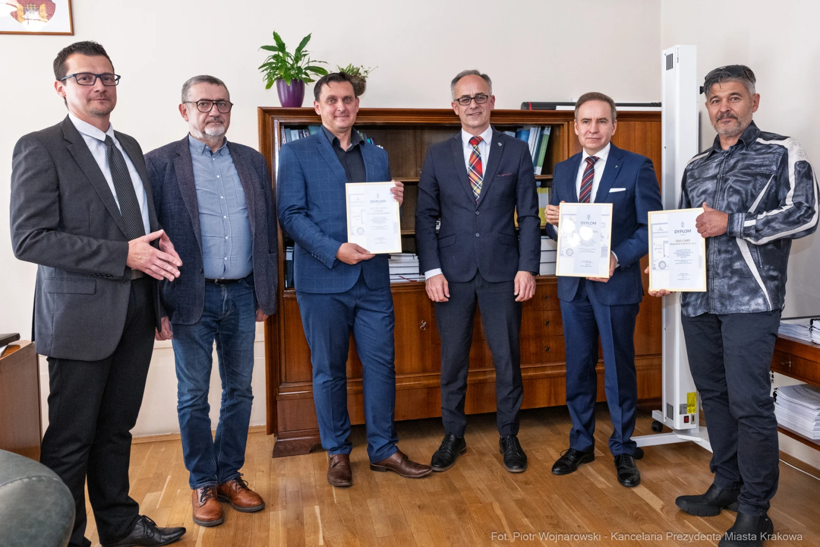 Grupa mężczyzn trzymających dyplomy w biurze.  Autor: Piotr Wojnarowski