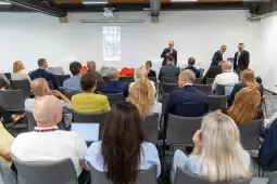 Konferencja z prelegentem i uczestnikami siedzącymi na sali.