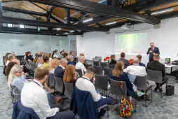 Konferencja z prelegentem i uczestnikami siedzącymi w sali.