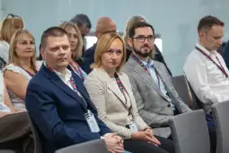 Grupa osób siedzących na konferencji, skupionych na prelekcji.