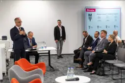 Konferencja z prelegentami i uczestnikami, prezentacja na ekranie w tle.