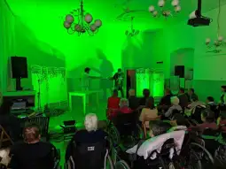 Występ artystyczny dla osób starszych w zielonym oświetleniu.