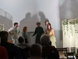 Grupa aktorów na scenie w trakcie przedstawienia teatralnego.