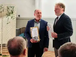 Mężczyźni trzymają dyplomy podczas uroczystości wręczenia nagród.