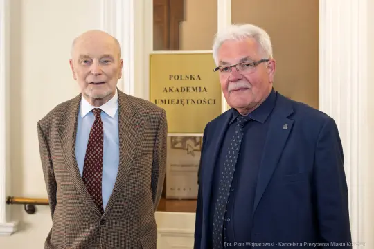 Dwaj mężczyźni w eleganckich garniturach stoją obok siebie w instytucji kulturalnej.