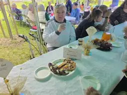 Mężczyzna siedzący przy stole z jedzeniem, obok talerz z ciastem i owocami.
