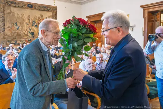 Uroczystość wręczenia kwiatów w sali z publicznością.