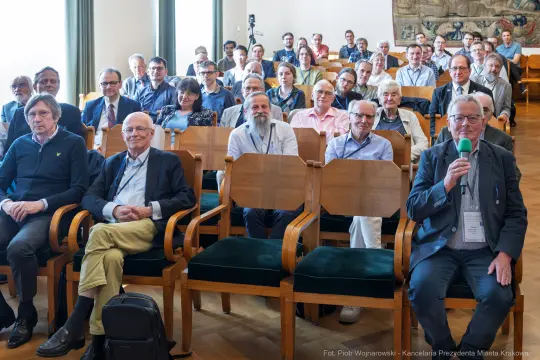 Grupa ludzi siedzących na sali konferencyjnej, uczestnicy wydarzenia.