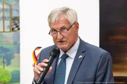 Mężczyzna w okularach trzyma mikrofon i przemawia.