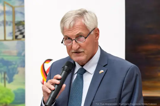 Mężczyzna w okularach trzyma mikrofon i przemawia.