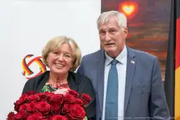 Para uśmiechniętych ludzi trzymająca bukiet czerwonych róż.