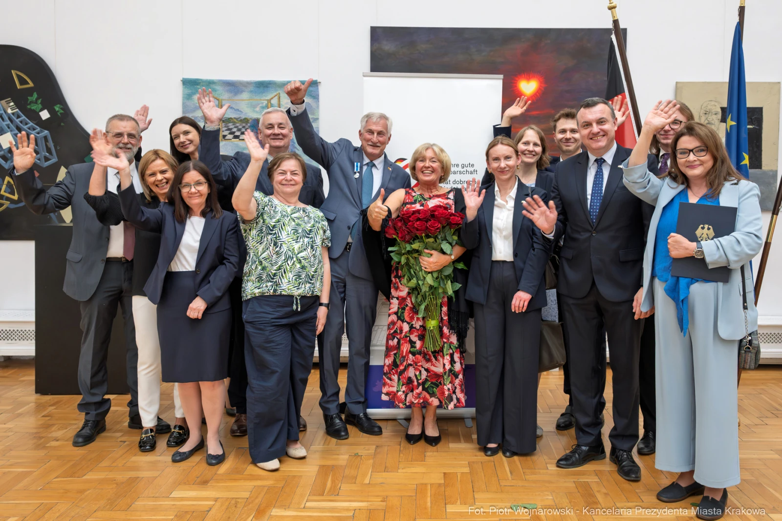 Grupa ludzi z uśmiechami, trzymających kwiaty, celebrujących wspólne osiągnięcie.  Autor: Piotr Wojnarowski