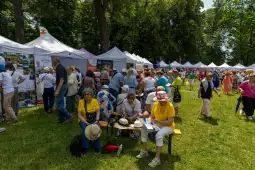 Tłum ludzi na festiwalu, stoiska wystawowe, zielona przestrzeń.
