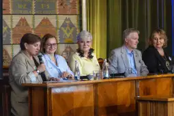 Panel dyskusyjny z pięcioma osobami przy stole, każda z mikrofonem lub notatkami.
