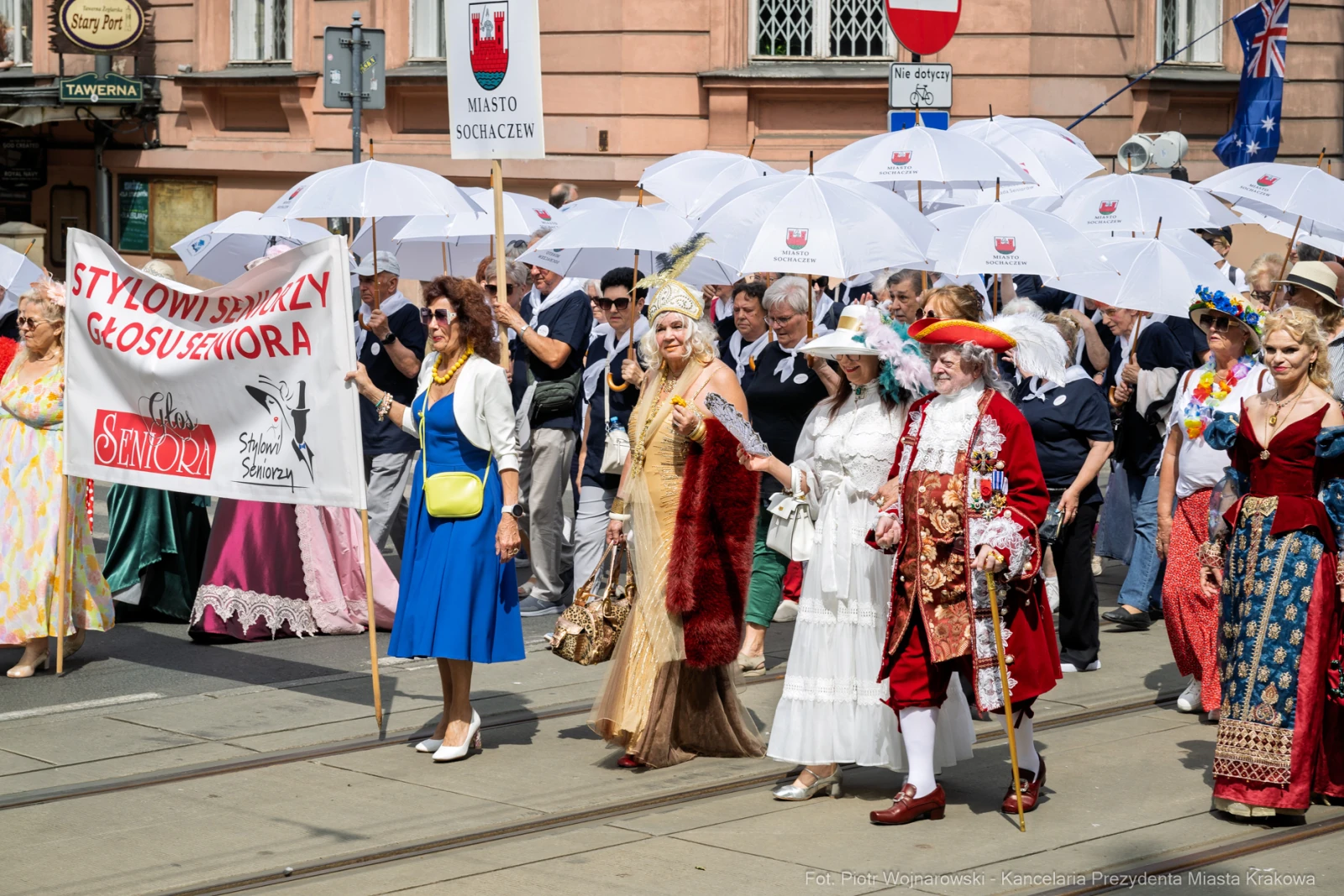 Parada z uczestnikami w strojach historycznych, trzymającymi parasole.  Autor: Piotr Wojnarowski