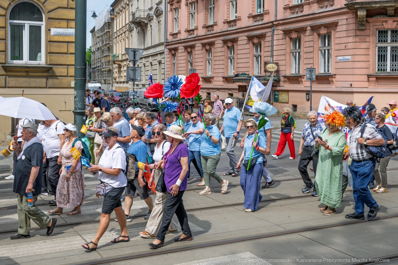 Tłum ludzi w kolorowych strojach, niosących flagi i parasole, idzie ulicą podczas parady.  Autor: Piotr Wojnarowski
