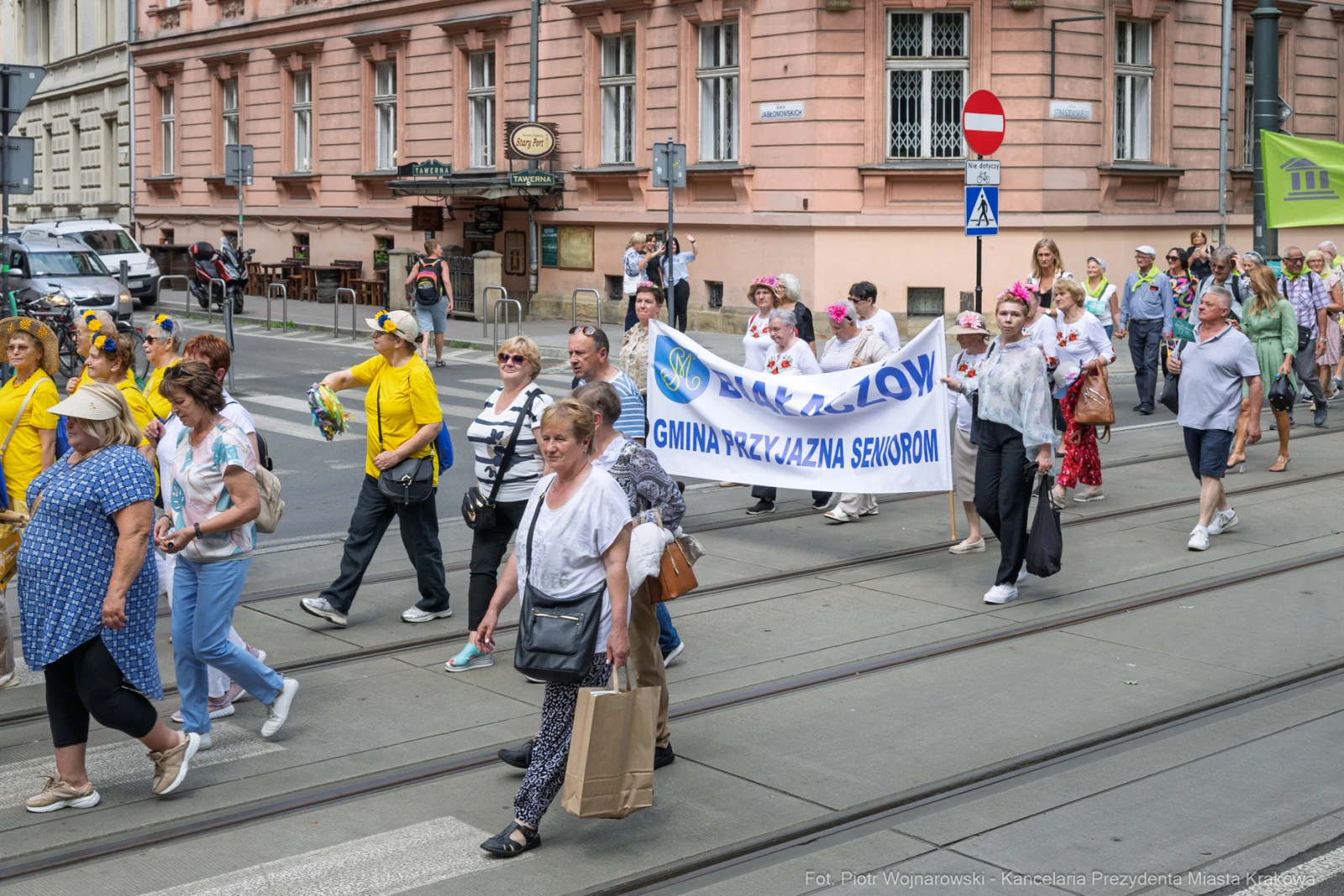Grupa ludzi w kolorowych strojach maszeruje z transparentem podczas wydarzenia.  Autor: Piotr Wojnarowski