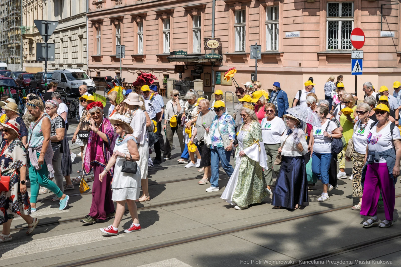 Grupa ludzi w kolorowych strojach i kapeluszach maszeruje ulicą.  Autor: Piotr Wojnarowski