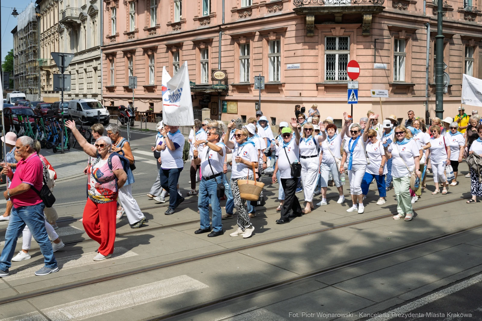 Grupa ludzi w białych koszulkach maszeruje ulicą, trzymając flagi i transparenty.  Autor: Piotr Wojnarowski