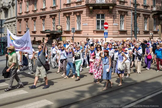 Grupa ludzi maszerująca ulicą, trzymająca transparenty i flagi.
