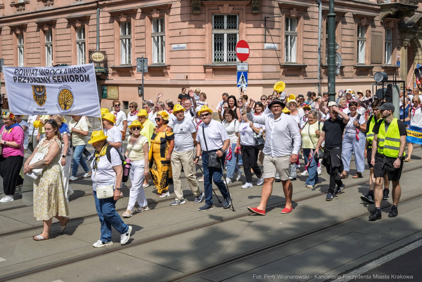 Marsz seniorów z transparentami i żółtymi nakryciami głowy na ulicach miasta.  Autor: Piotr Wojnarowski