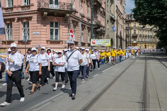 Marsz uczestników w białych i żółtych koszulkach na ulicach miasta.