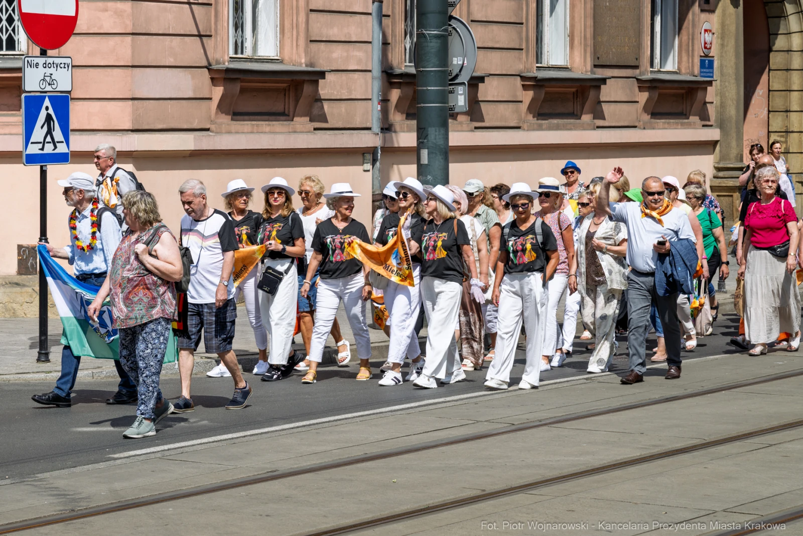 Grupa osób w białych ubraniach i kapeluszach idzie ulicą podczas wydarzenia.  Autor: Piotr Wojnarowski