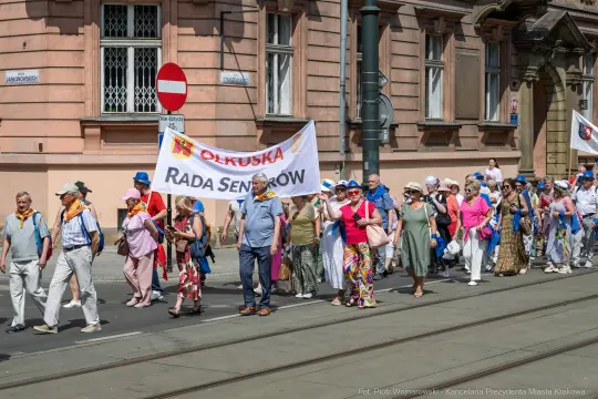 Grupa ludzi idąca w marszu z transparentem Rada Seniorów.