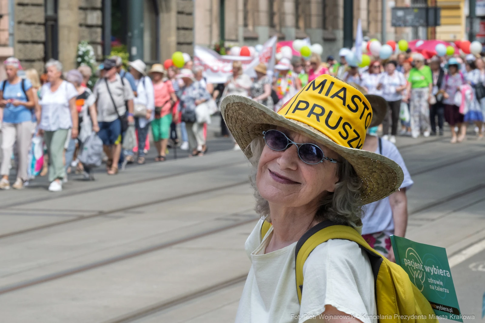 Kobieta w kapeluszu z napisem Miasto Pruszków, uśmiechająca się podczas marszu z balonami.  Autor: Piotr Wojnarowski