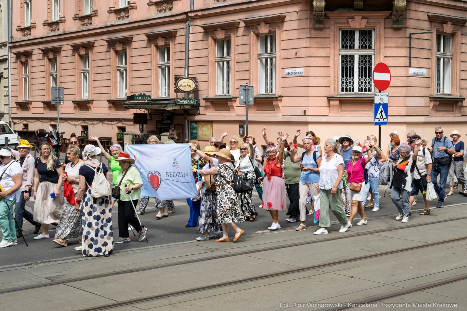 Grupa ludzi w kolorowych strojach maszeruje ulicą, trzymając transparenty.  Autor: Piotr Wojnarowski