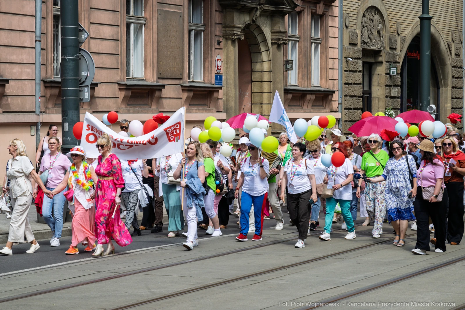 Grupa ludzi z balonami i transparentami uczestniczy w marszu ulicami miasta.  Autor: Piotr Wojnarowski