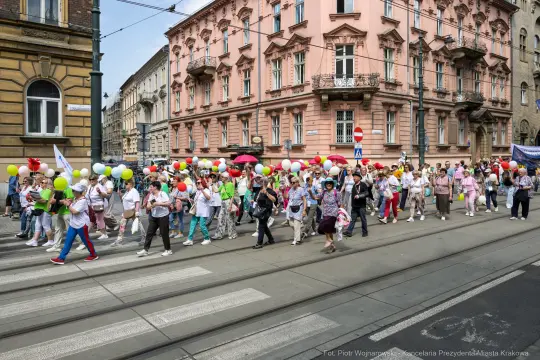Grupa ludzi z balonami maszerująca ulicą w mieście.