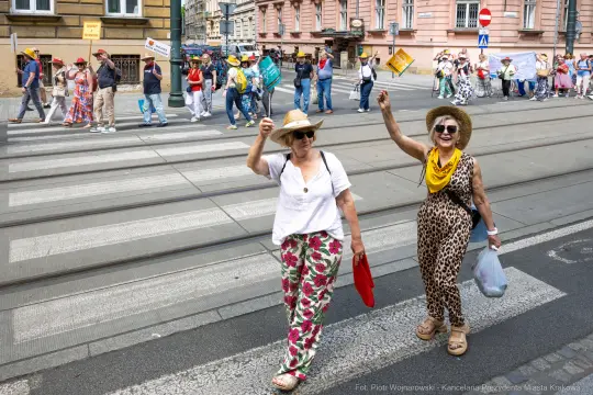 Dwie kobiety w kolorowych strojach machają rękami podczas parady.