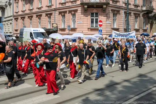 Grupa ludzi w kolorowych strojach idzie ulicą podczas parady.