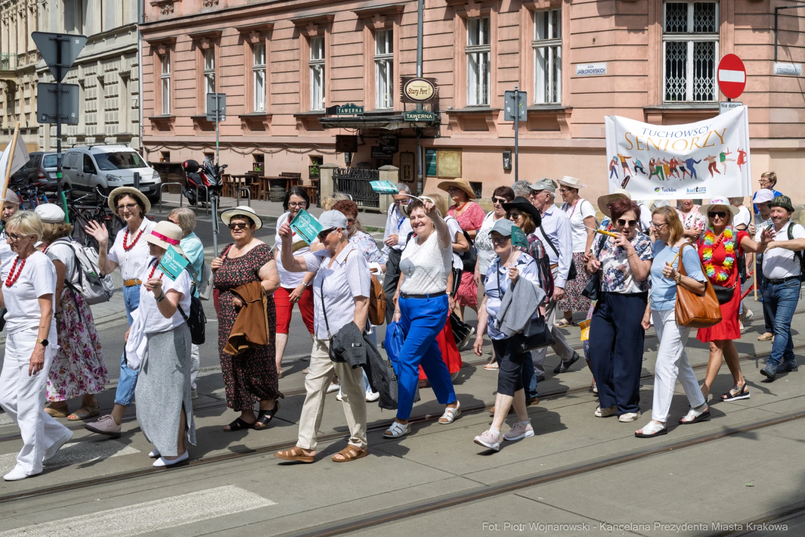 Grupa seniorów w trakcie parady, trzymających ulotki i uśmiechających się.  Autor: Piotr Wojnarowski