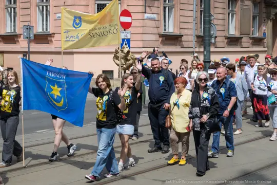 Grupa ludzi z flagami i transparentami podczas parady w Tarnowie.
