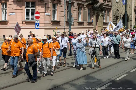 Grupa ludzi w pomarańczowych koszulkach idzie ulicą podczas marszu.
