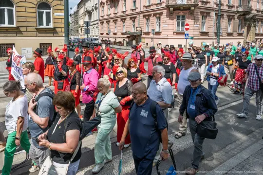 Tłum ludzi w kolorowych strojach maszeruje ulicą podczas wydarzenia kulturalnego.