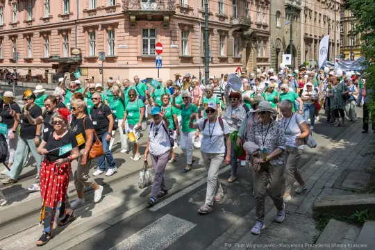 Tłum ludzi w zielonych koszulkach idzie ulicą podczas wydarzenia.