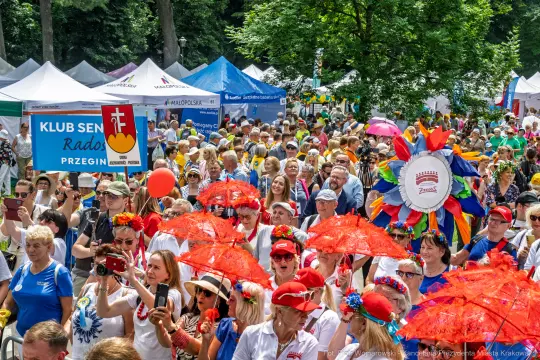 Tłum ludzi w kolorowych strojach, trzymających parasole, podczas festiwalu.
