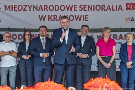 Mężczyzna w garniturze przemawia do grupy ludzi na wydarzeniu w Krakowie.