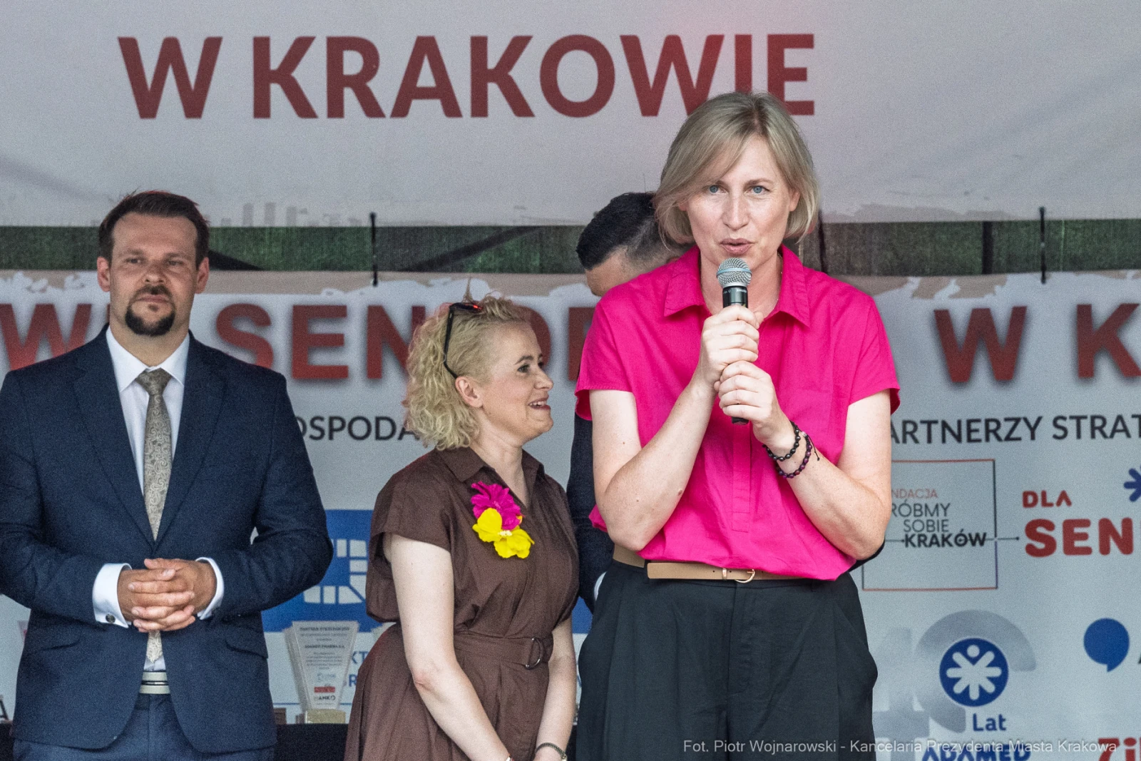 Kobieta w różowej koszuli przemawia do zgromadzenia, w tle inni uczestnicy wydarzenia.  Autor: Piotr Wojnarowski