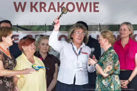 Kobieta trzymająca klucz, przemawia do zgromadzenia, w tle inne uczestniczki wydarzenia.