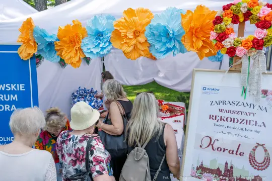 Warsztaty rękodzieła z koralami, kolorowe dekoracje i uczestnicy w tle.